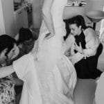 Friends helping bride to get dressed on the wedding morning