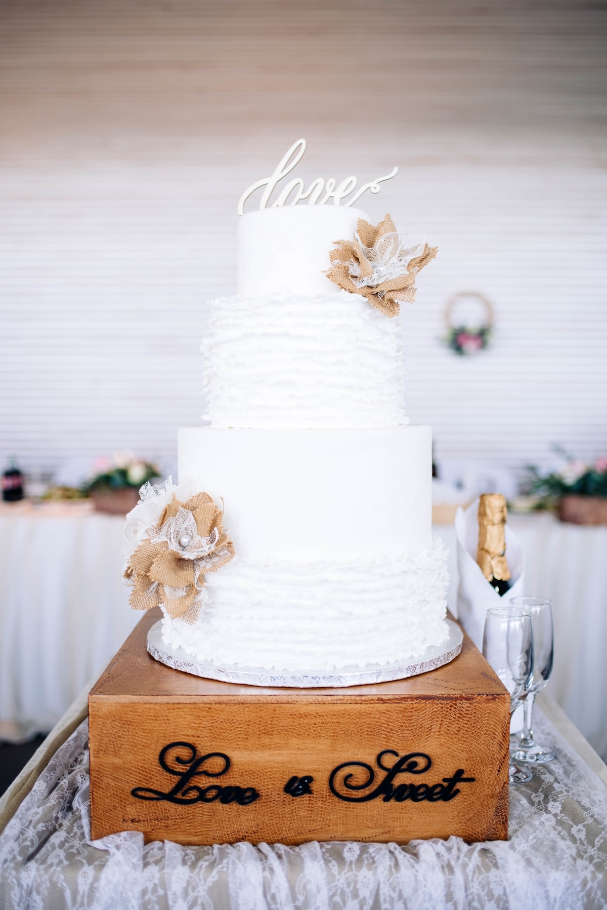 Λευκή τούρτα γάμου με φιόγκους από λινάτσα